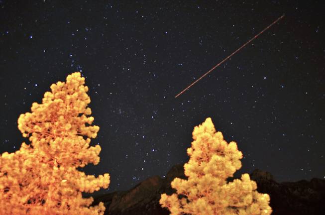 A long time exposure catches a plane flying over Mt. Charleston and the star-lit hills, below. on Saturday, Mar. 9, 2013. 
